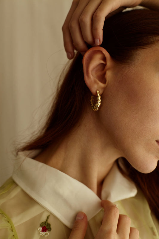 indossato orecchino con forme sinuose e morbide interamente realizzato a mano da piqué a riva del garda