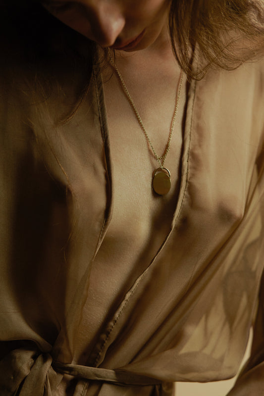 dettaglio della collana in oro giallo pallido della serie dune con pendente ovale indossata